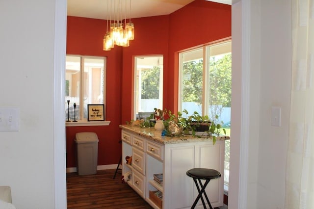 interior space featuring pendant lighting, an inviting chandelier, light stone counters, dark hardwood / wood-style flooring, and white cabinetry