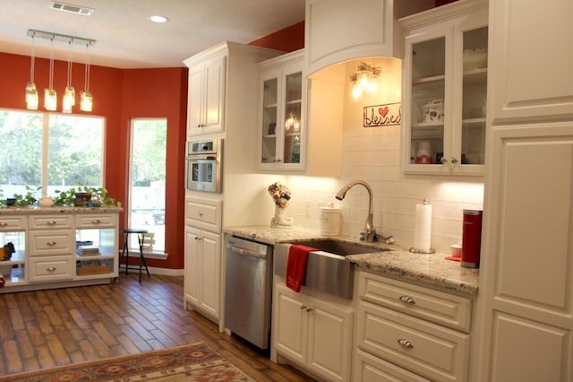 kitchen with light stone countertops, white cabinetry, dishwasher, hanging light fixtures, and sink