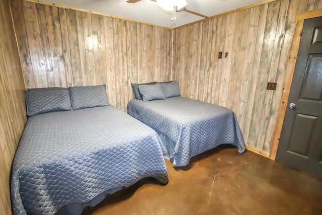 bedroom with ceiling fan, concrete flooring, and wood walls