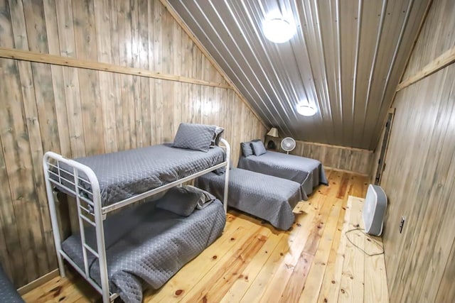 bedroom featuring wooden walls, hardwood / wood-style flooring, and lofted ceiling