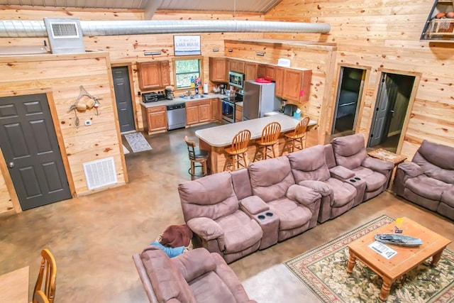 living room with beamed ceiling, wooden walls, and sink