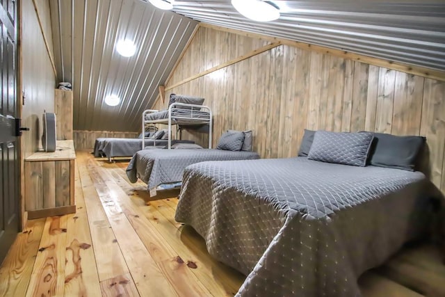 bedroom with wood walls, wood-type flooring, and lofted ceiling