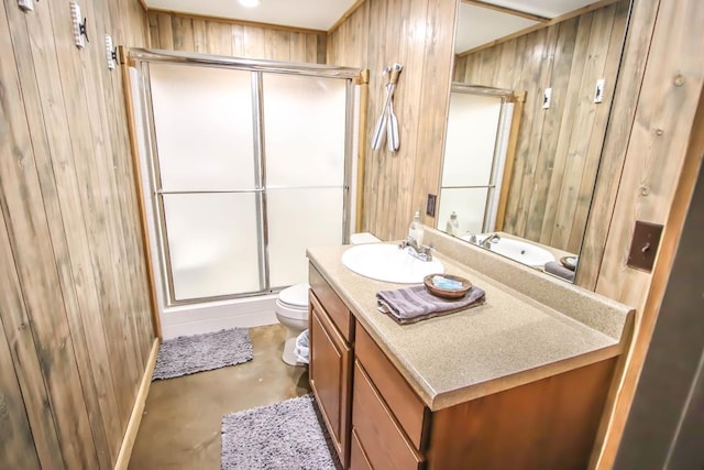 bathroom featuring vanity, toilet, a shower with shower door, and wooden walls