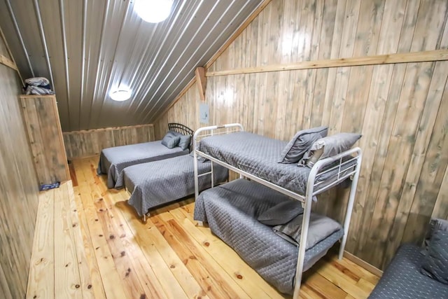 bedroom with wooden walls, hardwood / wood-style floors, and lofted ceiling