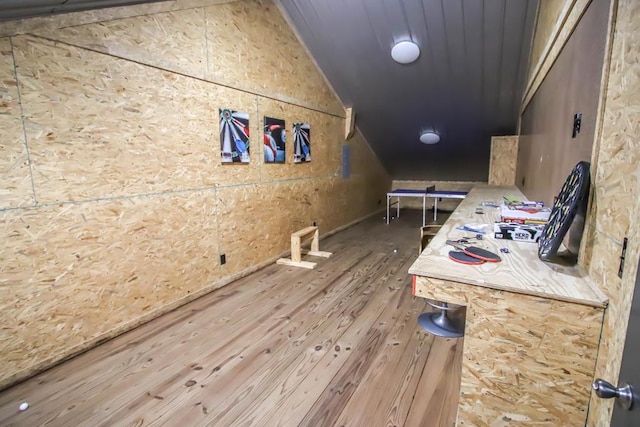 bonus room featuring wood walls, wood-type flooring, and vaulted ceiling