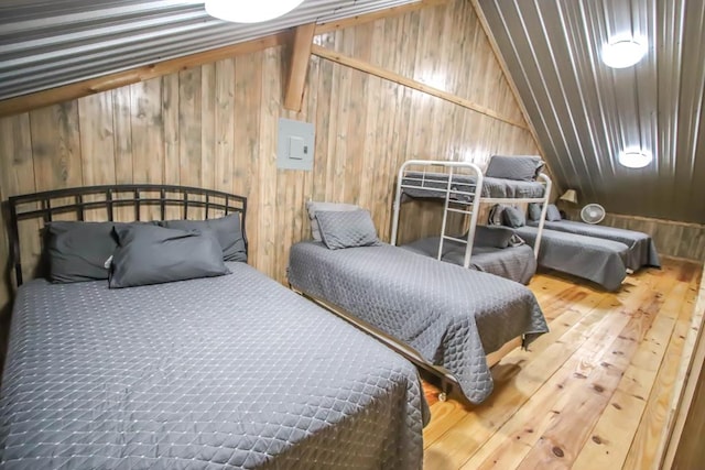 bedroom featuring hardwood / wood-style floors, wooden walls, and lofted ceiling