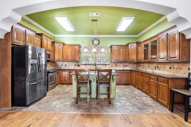 kitchen with a kitchen bar, appliances with stainless steel finishes, hardwood / wood-style flooring, and hanging light fixtures