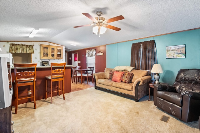 living room featuring light carpet, a textured ceiling, vaulted ceiling, and ceiling fan