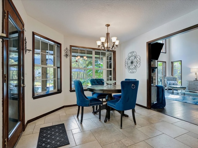 dining area with a wealth of natural light, baseboards, a notable chandelier, and a textured ceiling