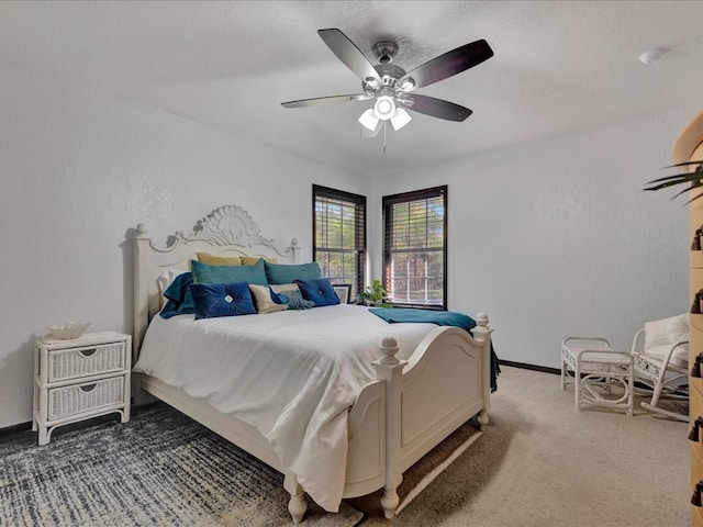 bedroom featuring a ceiling fan, baseboards, a textured wall, and light carpet