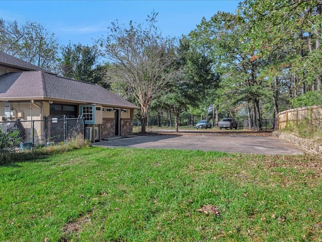 view of yard featuring aphalt driveway and fence