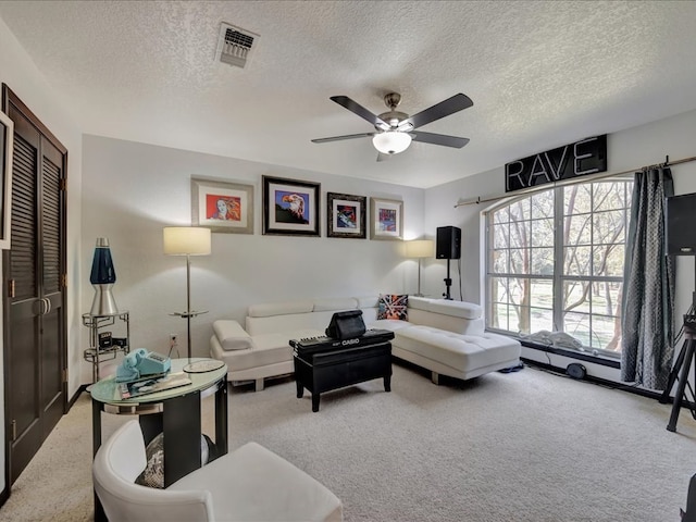 living area with a ceiling fan, carpet, visible vents, and a textured ceiling