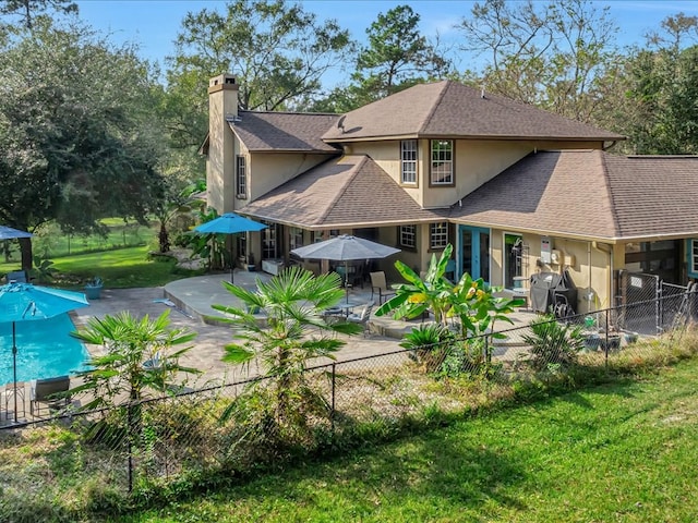 rear view of property featuring a patio area, stucco siding, a chimney, and a fenced backyard