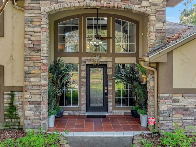 property entrance with stone siding, stucco siding, and roof with shingles