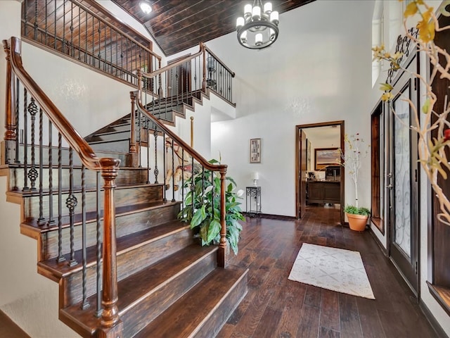 foyer entrance featuring baseboards, wood ceiling, a towering ceiling, hardwood / wood-style flooring, and a notable chandelier