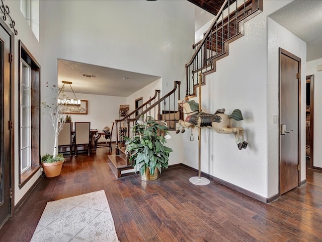 entryway featuring visible vents, hardwood / wood-style flooring, baseboards, a towering ceiling, and stairs