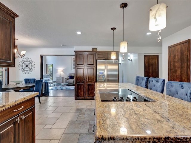 kitchen with light stone counters, black electric cooktop, pendant lighting, stainless steel fridge with ice dispenser, and a kitchen island