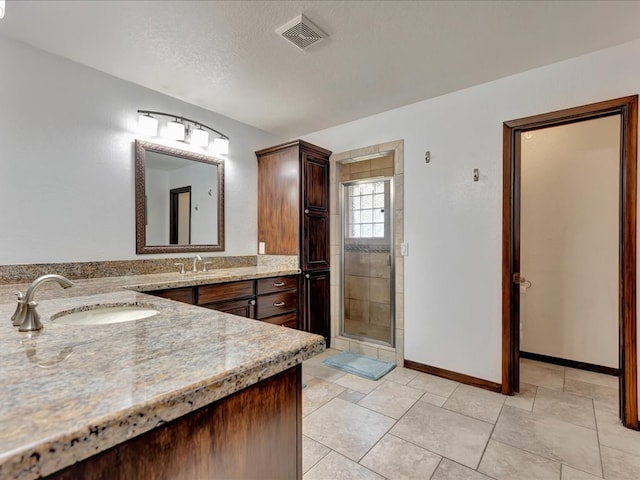 full bathroom with visible vents, a shower stall, baseboards, vanity, and a textured ceiling