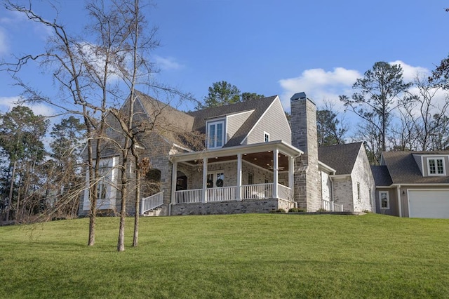 view of front of property featuring a front lawn, a garage, covered porch, and stone siding