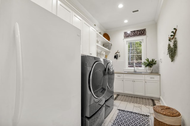 clothes washing area with washer and clothes dryer, visible vents, cabinet space, and crown molding