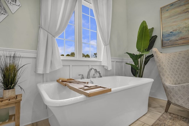 full bathroom with a freestanding tub, a wainscoted wall, and a decorative wall