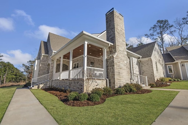 view of home's exterior with stone siding, a lawn, covered porch, and a chimney