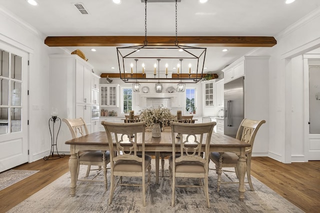 dining space with visible vents, beam ceiling, and wood finished floors