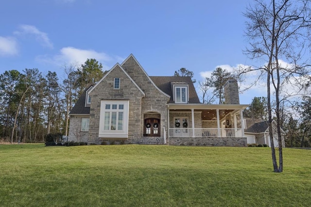 view of front of house with stone siding, covered porch, and a front yard