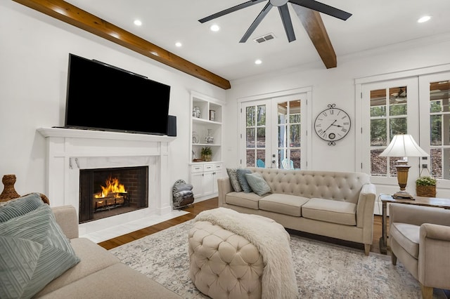 living area with a high end fireplace, visible vents, beam ceiling, french doors, and wood finished floors