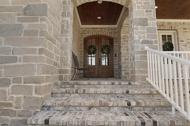 view of exterior entry with brick siding, stone siding, and french doors