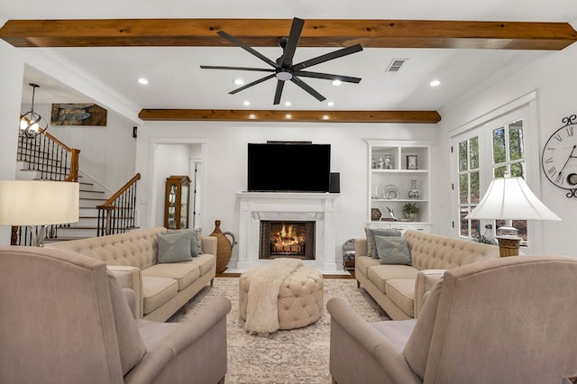 living room featuring visible vents, beam ceiling, ceiling fan with notable chandelier, stairway, and a fireplace