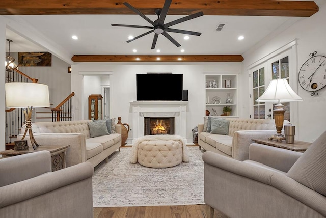 living room featuring beamed ceiling, a ceiling fan, visible vents, and wood finished floors