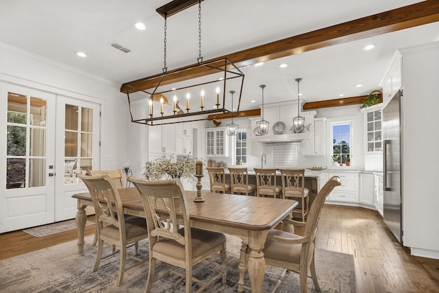 dining space featuring visible vents, beam ceiling, hardwood / wood-style flooring, french doors, and crown molding