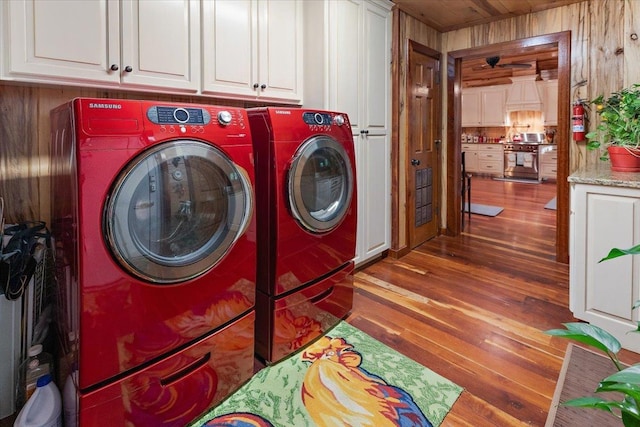 334 Pineknot Ln, Milam, TX 75959 - laundry area featuring washer and dryer, cabinet space, wooden walls, and wood finished floors