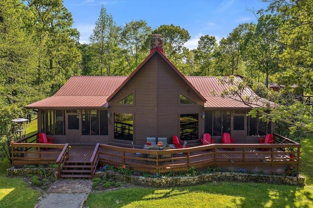 rear view of house featuring a lawn, a sunroom, and a wooden deck