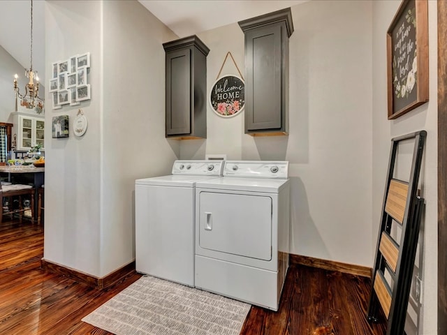 clothes washing area featuring an inviting chandelier, dark wood-style flooring, baseboards, washing machine and clothes dryer, and cabinet space