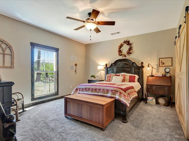 bedroom featuring visible vents, a barn door, carpet flooring, and a ceiling fan