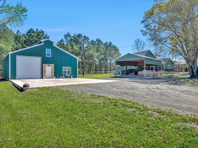 view of pole building with dirt driveway and a lawn
