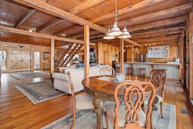 dining area featuring wooden walls, visible vents, and hardwood / wood-style floors