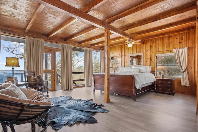 bedroom with wood walls, access to exterior, beamed ceiling, and multiple windows