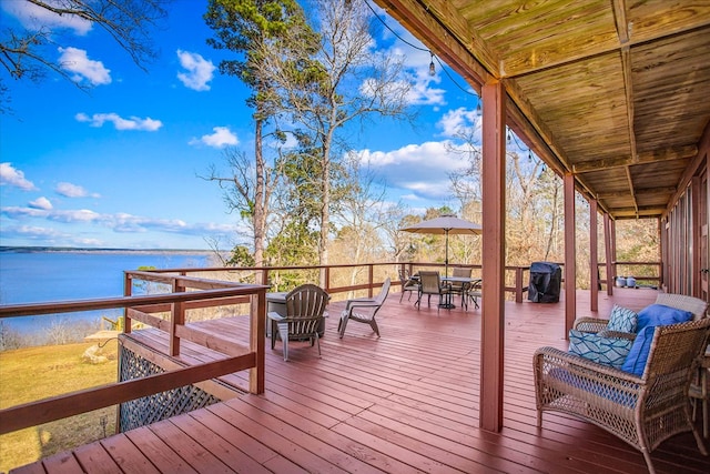 deck with a water view and outdoor dining area