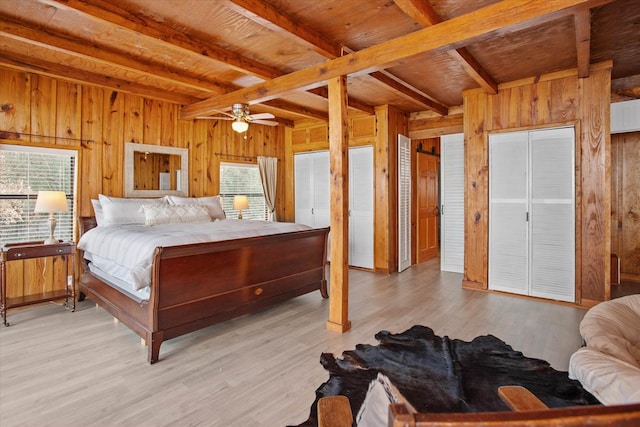 bedroom featuring wooden walls, beamed ceiling, light wood finished floors, and wooden ceiling