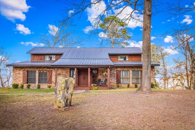 view of front of home featuring metal roof, covered porch, and brick siding
