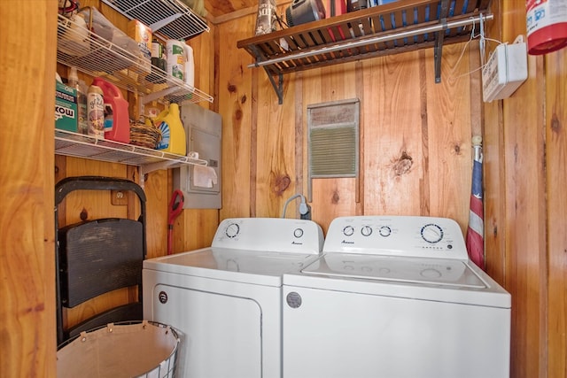 washroom with laundry area, separate washer and dryer, and wooden walls