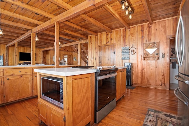 kitchen with light wood-style flooring, wood ceiling, stainless steel appliances, wooden walls, and beam ceiling