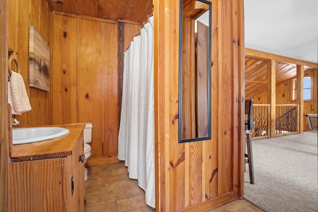 bathroom with wooden walls, toilet, curtained shower, and vanity