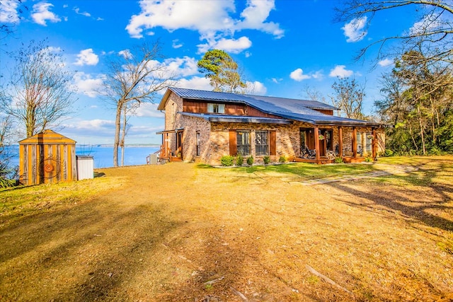 back of property featuring brick siding, metal roof, a lawn, and an outbuilding