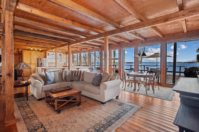 living area with a water view, beamed ceiling, wooden ceiling, and wood finished floors