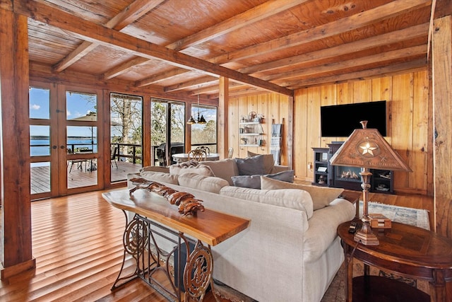 living room featuring wooden walls, french doors, beamed ceiling, wooden ceiling, and wood finished floors