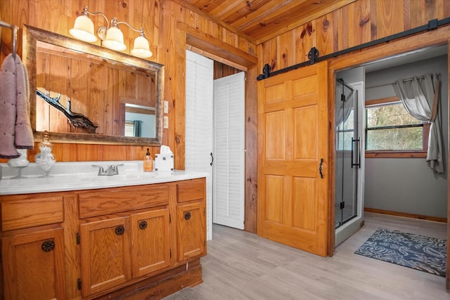 full bath with a shower stall, wood finished floors, wood walls, and vanity